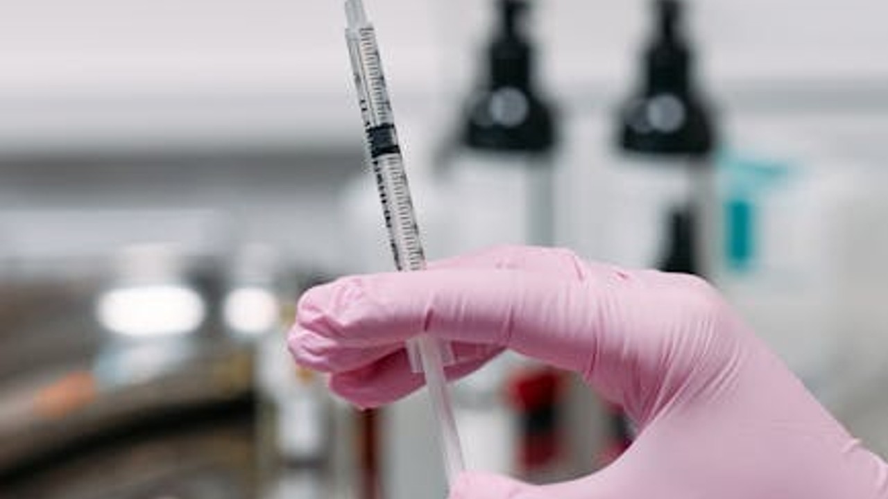 A close-up of a medical professional preparing a syringe for injection, illustrating the administration of peptides.