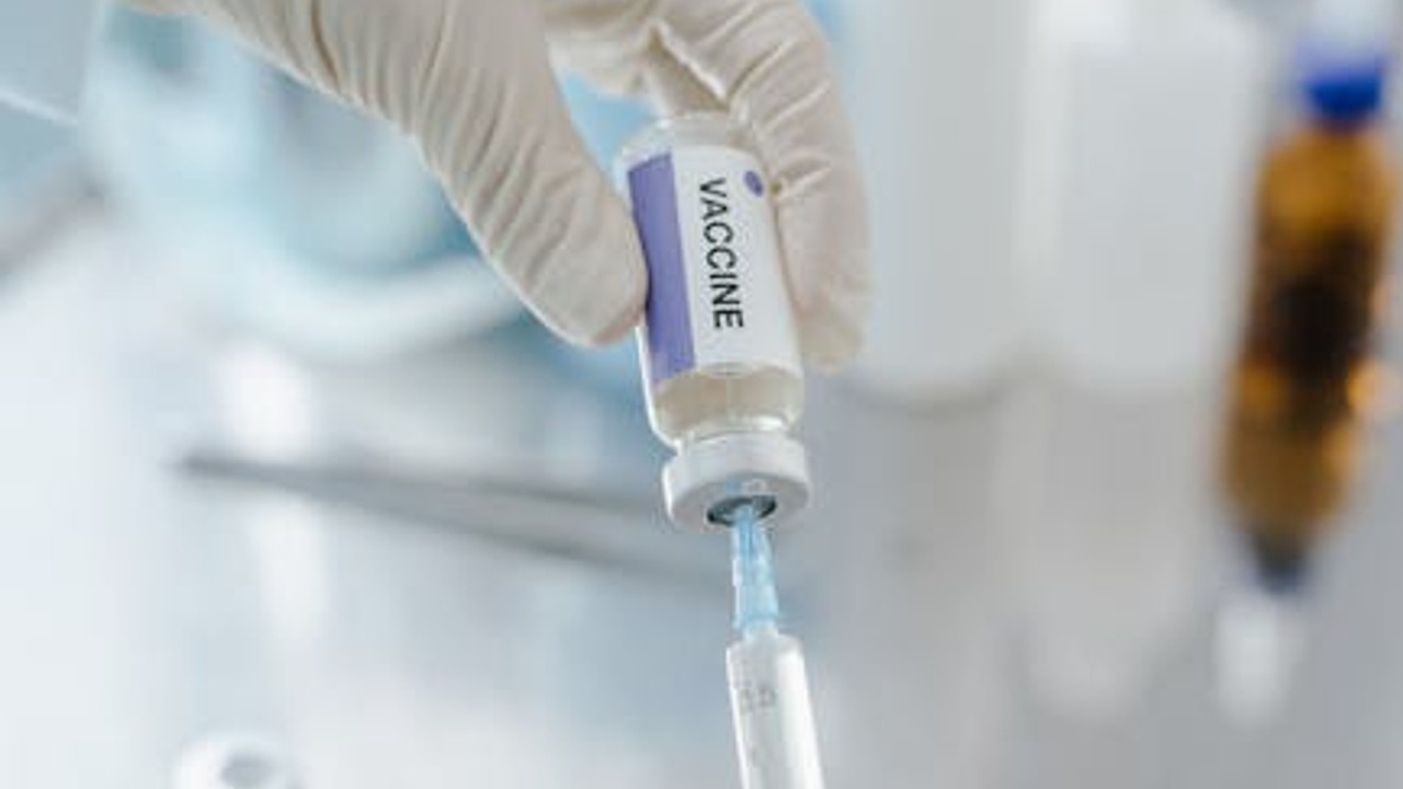 Close-up of a syringe being filled with clear liquid from a vial.