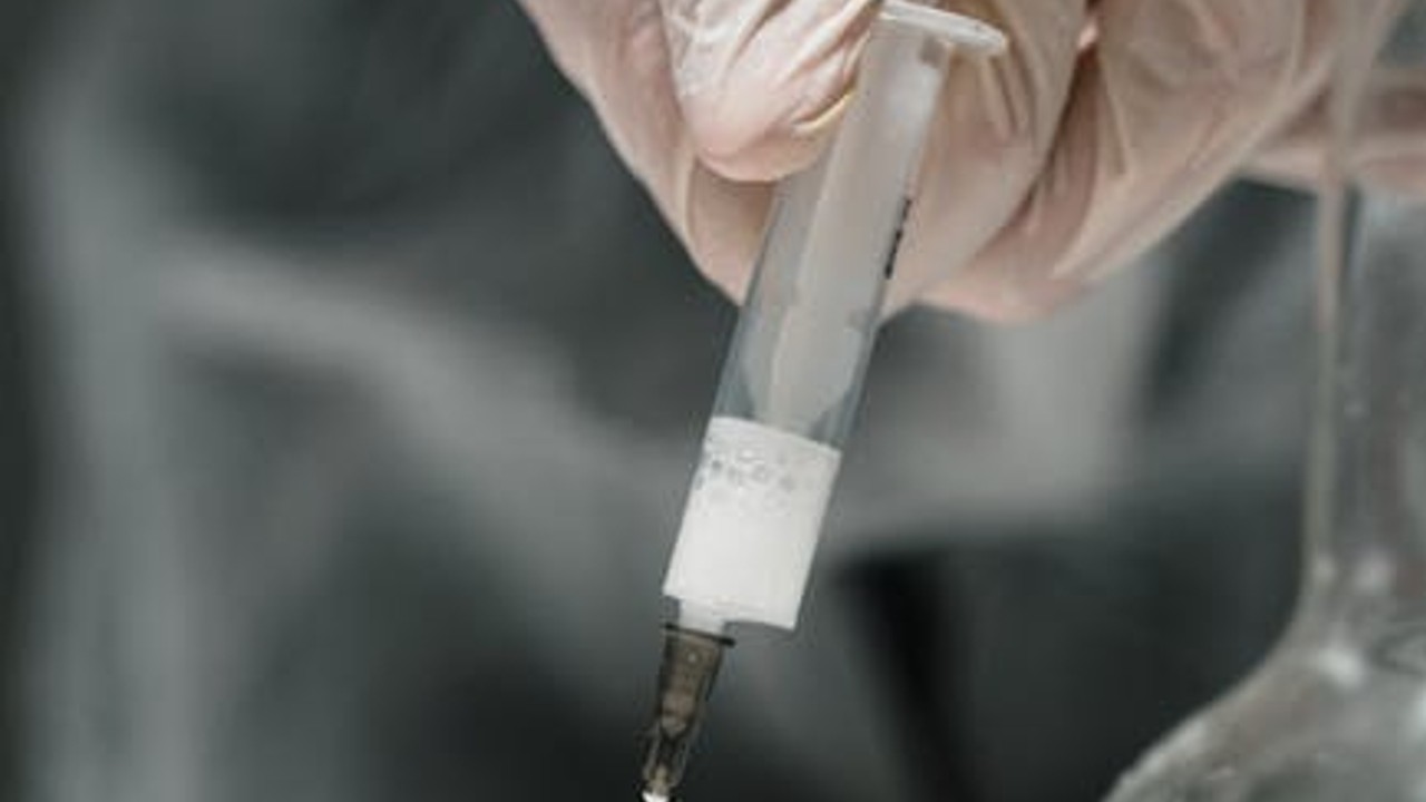 A sterile syringe drawing liquid from a vial, demonstrating a step in peptide reconstitution.