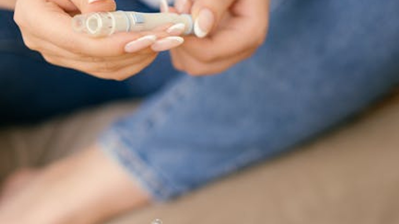 A close-up of a hand carefully drawing liquid into a syringe from a vial.