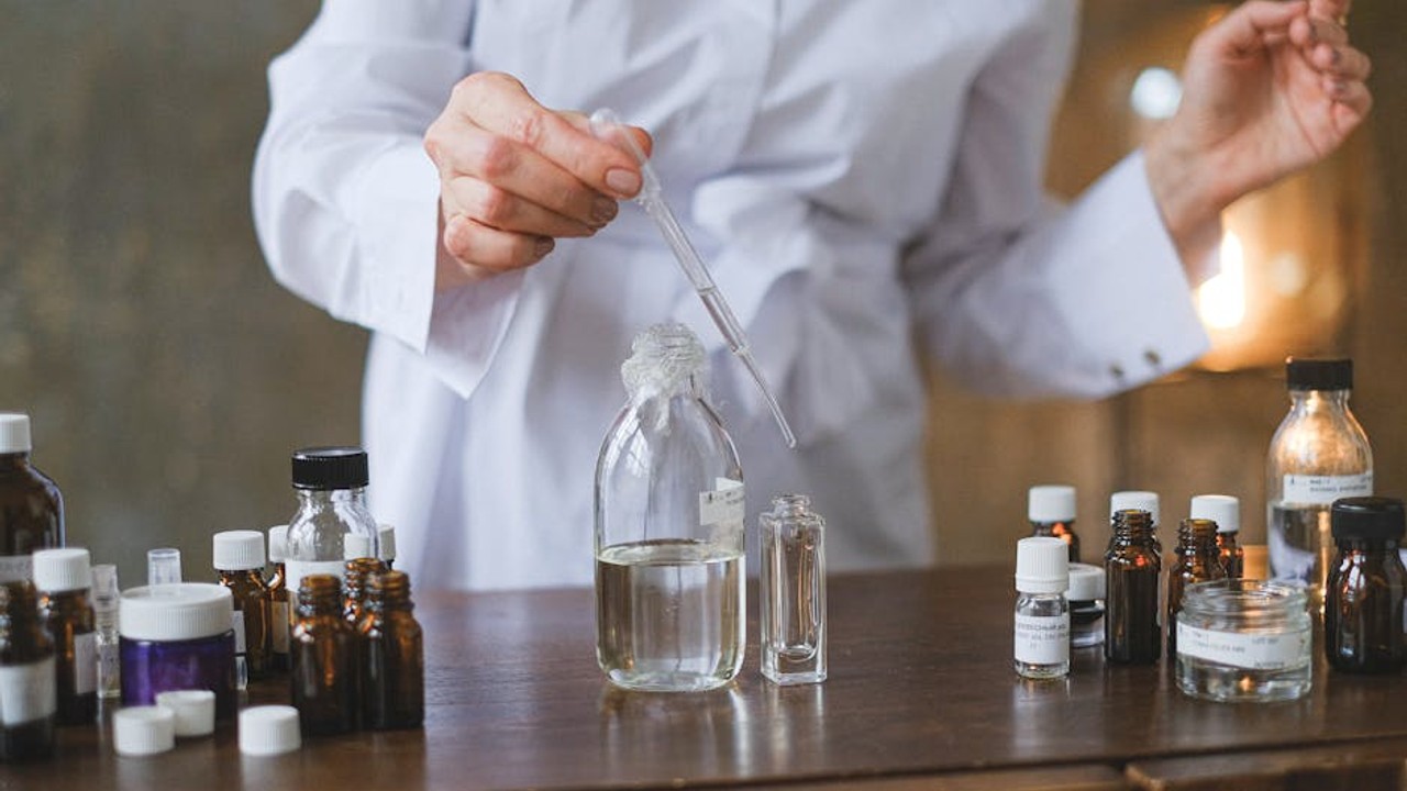 A lab technician carefully pipetting a clear liquid into a small vial, representing the scientific formulation of peptides for skincare.